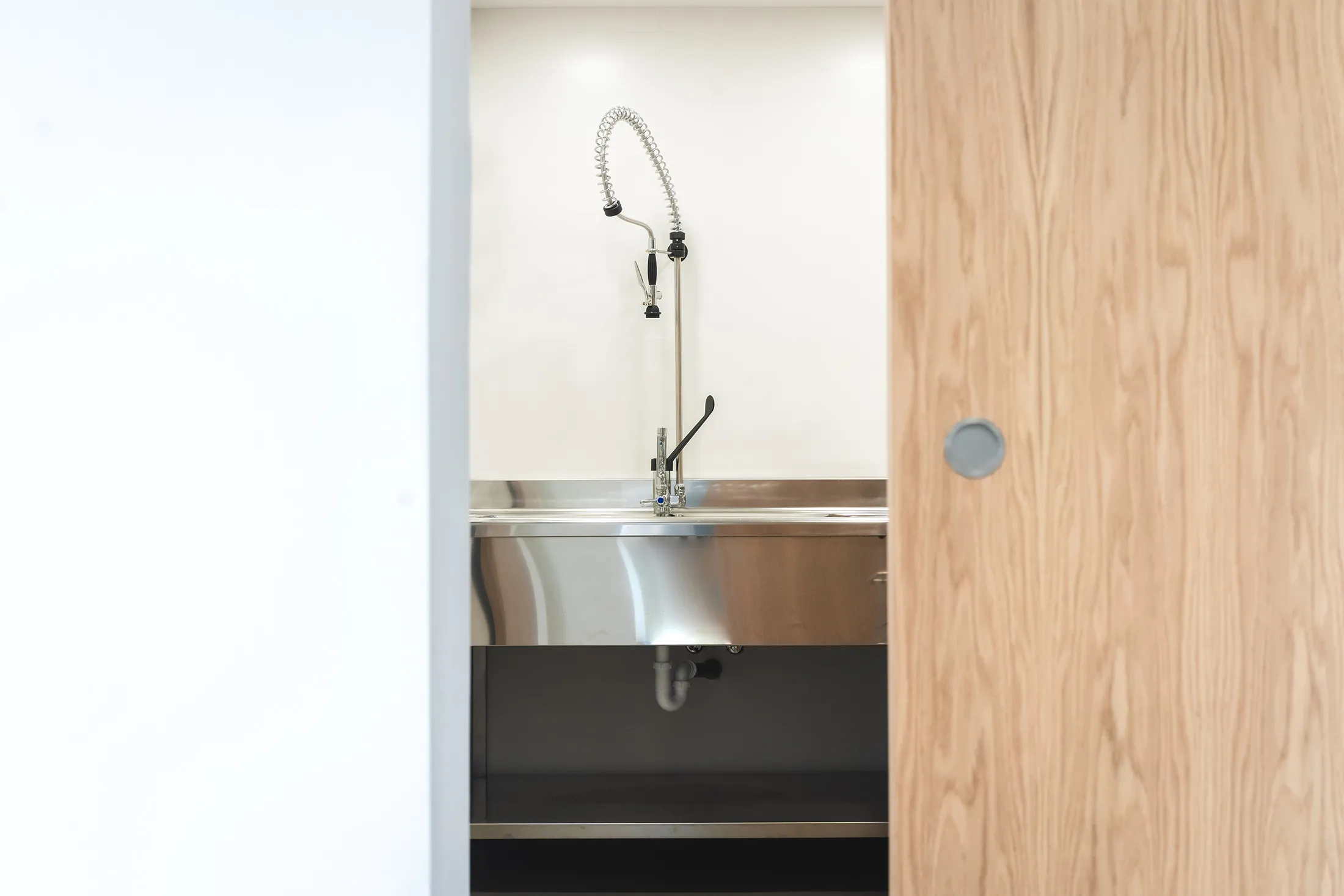 Detalle de lavabo de acero inoxidable integrado en mobiliario de madera